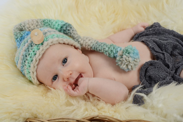 Baby auf Schafsfell mit Mütze und Tuch